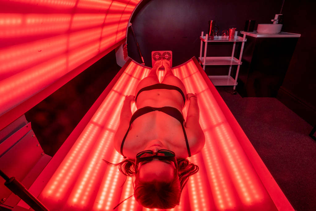 A woman on a bed, experiencing red light therapy for skin rejuvenation.